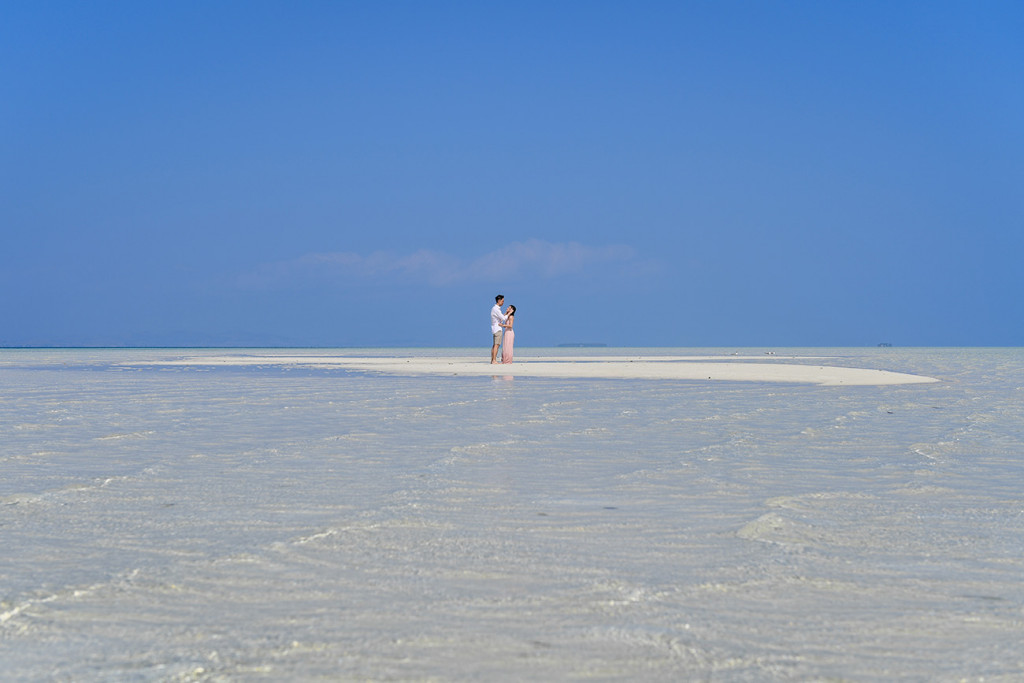 The couple kiss against the deep blue skies at Lomani Island Resort
