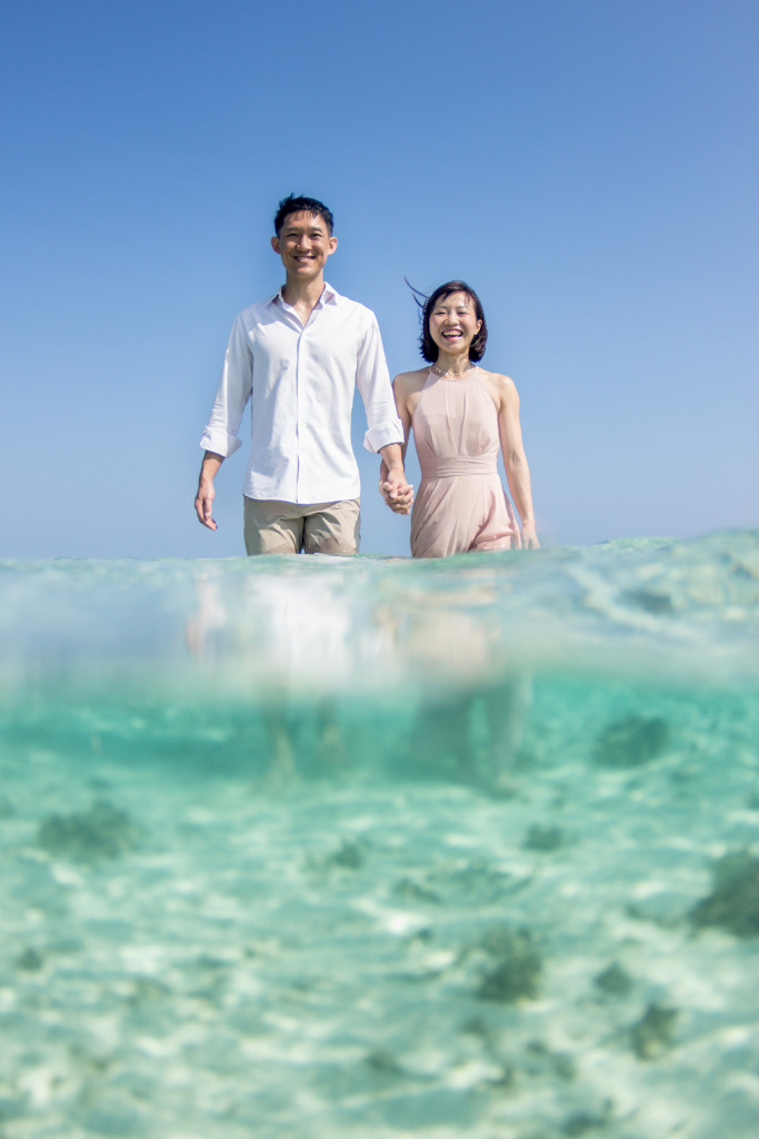 A partial underwater shot of the couple holding hands and strolling towards camera