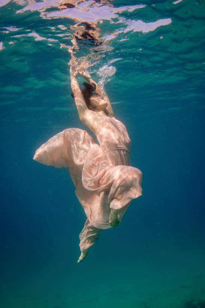 A portrait of the bride gloriously swimming underwater