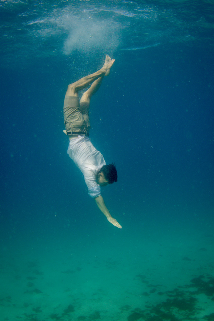 The groom dives underwater towards the floor of the sea
