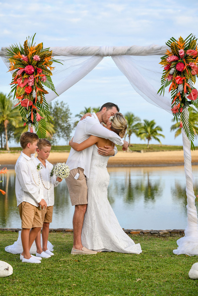 The groom passionately kisses his bride behind the stunning ocean