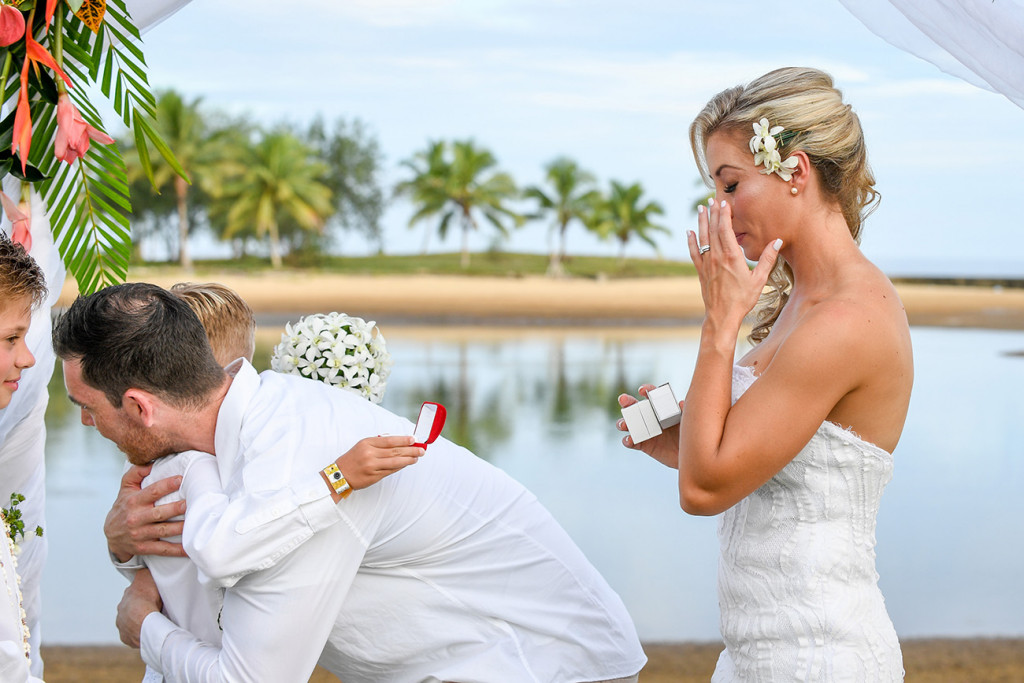 The bride wipes a tear as her groom hugs their sons