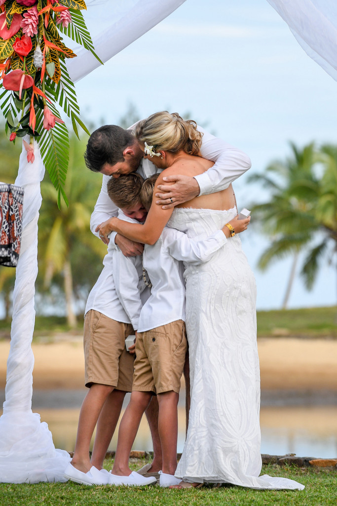 The newly married family embrace in a tight hug after being officially married