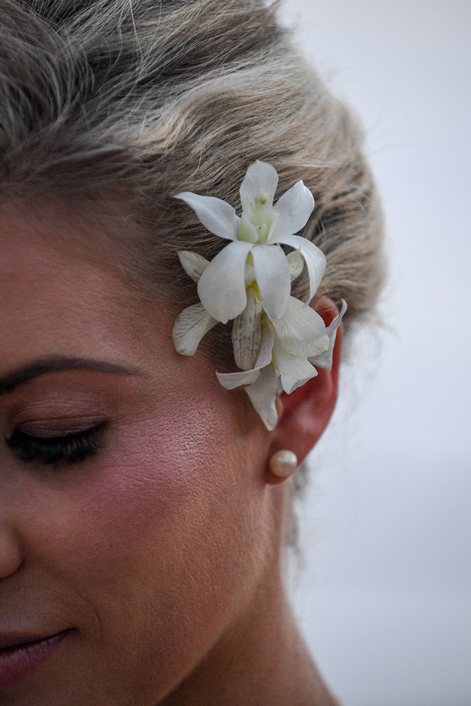 Closeup on frangipani flower tucked behind the bride's hair