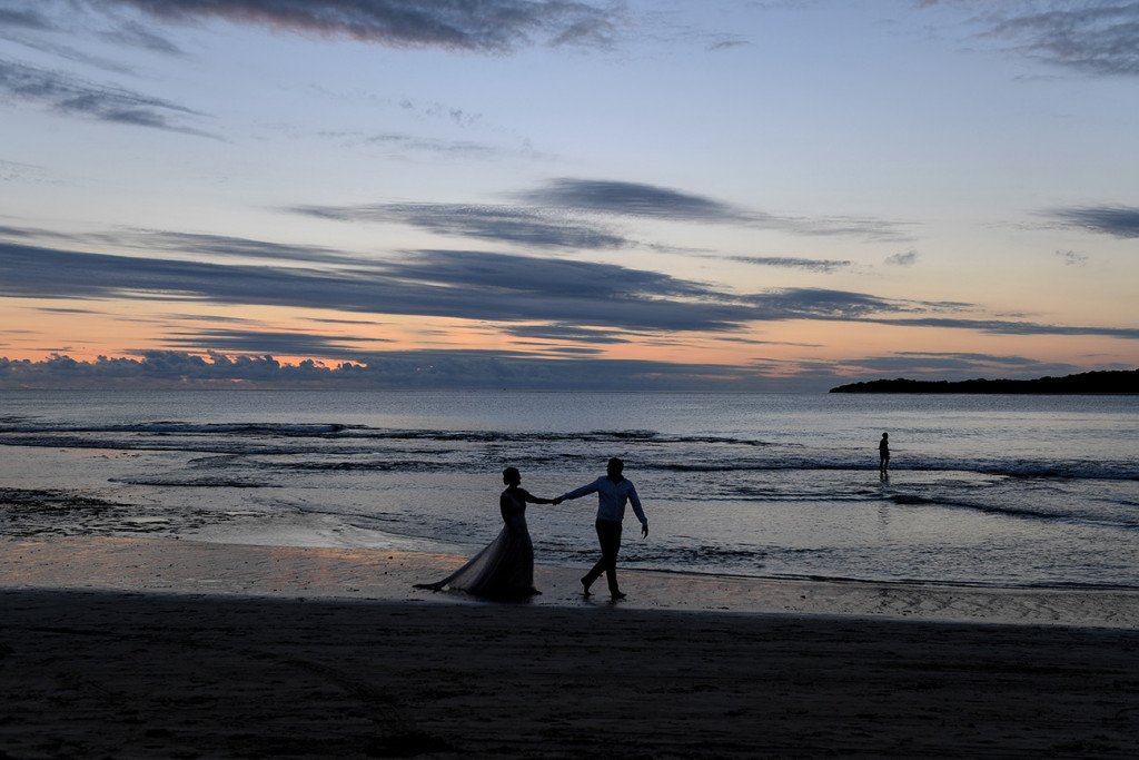 A silhouette of the couple playing in the ocean at sunset