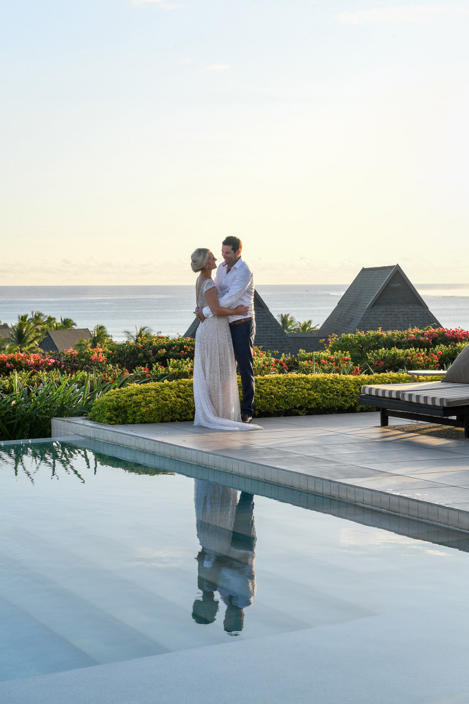 Reflection of the couple in the pool with the stunning Pacific in the background