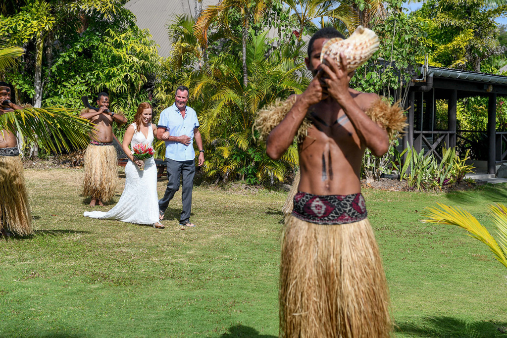 A traditional Fiji warrior announces bride's arrival using a shell as a horn