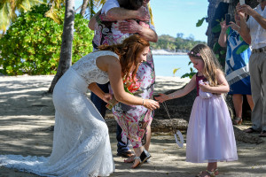 Bride and flowergirl play as guests mingle after their beach wedding