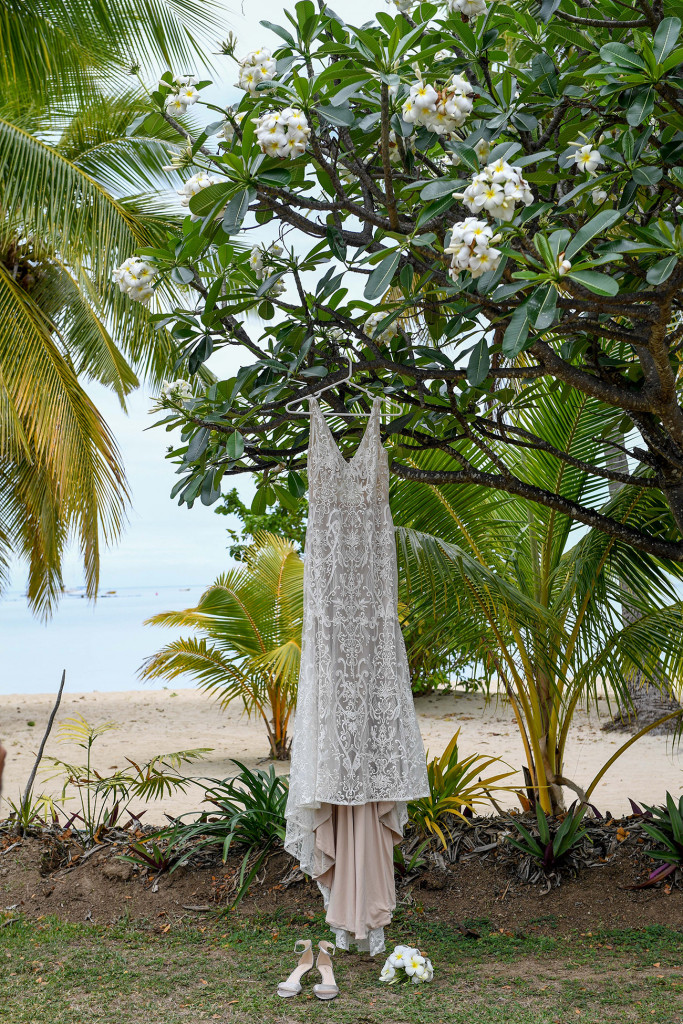 An egg-white lace dress by Luv bridal hangs from tropical frangipani tree