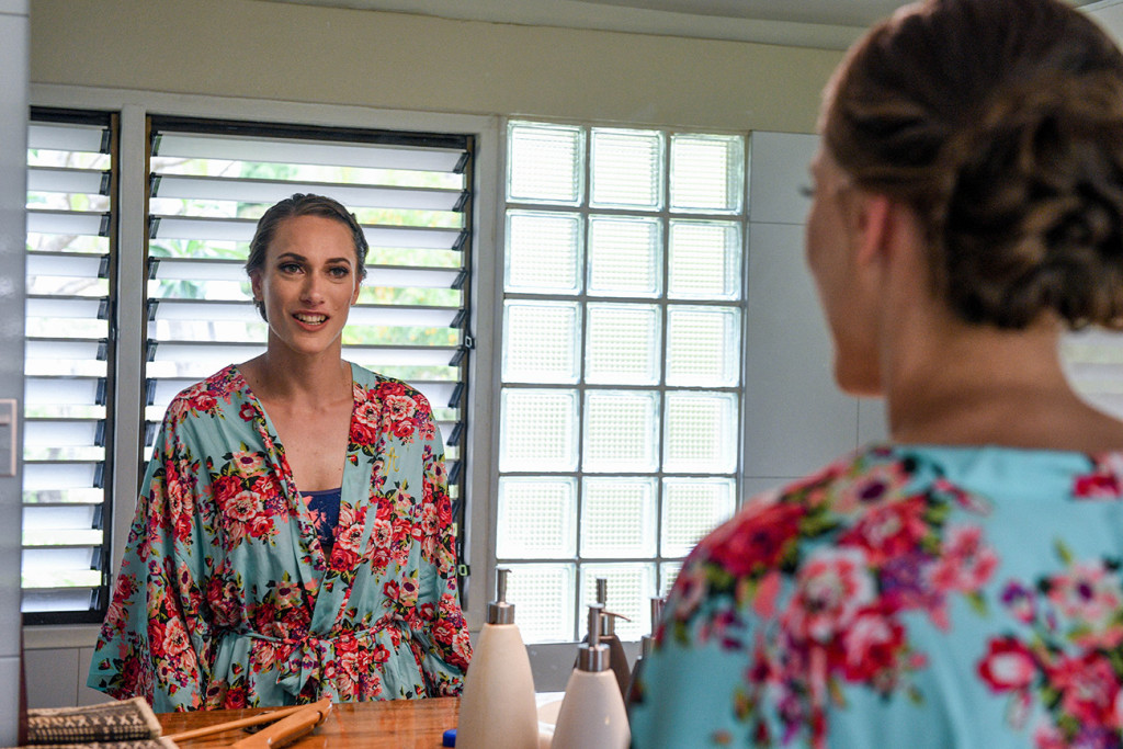 The stunning bride in a floral, blue kimono admires her reflection in the mirror