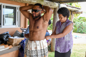 The Fiji groom raises his hand as a relative ties his masi