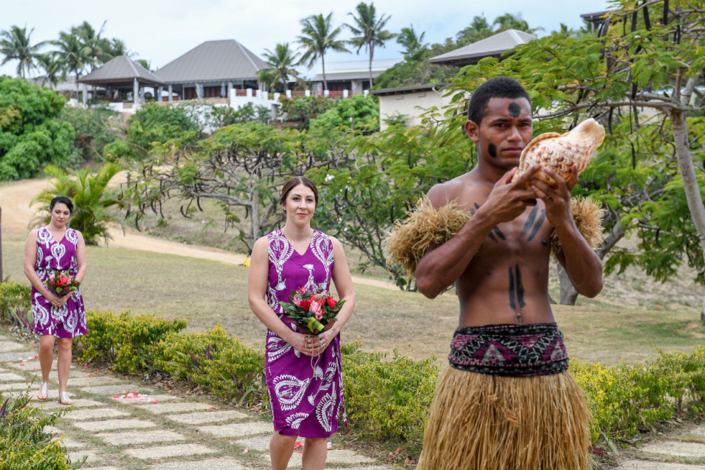Bridemaid in purple Fiji dress behind traditionally clad Fiji groomsman