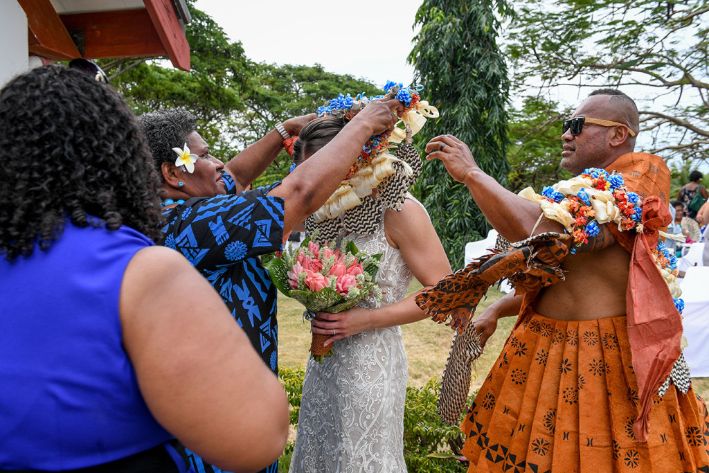 The groom's family dresses the bride with a traditional Fiji wreath