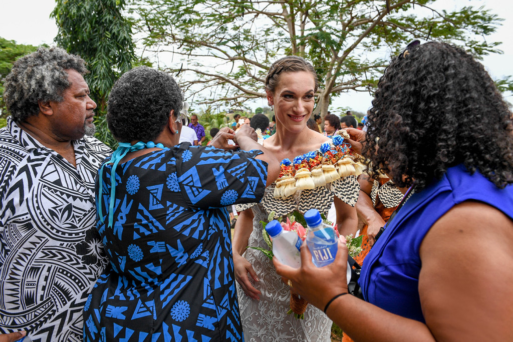 The groom's family admires the bride in her traditional Fiji wreath