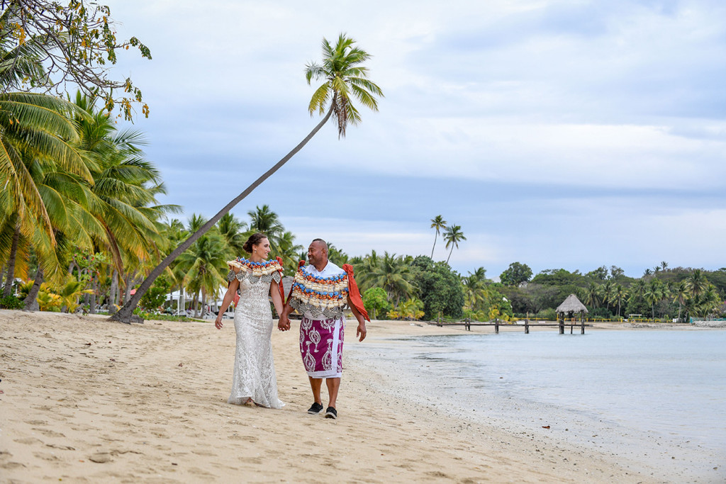 The newly married couple strolls on the shores of the Pacific at Musket Cove