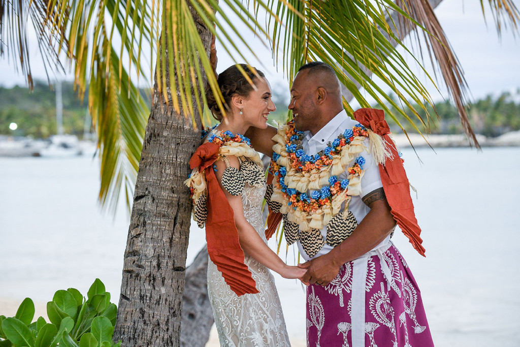 The bride and groom share a passionate moment under the palm tree