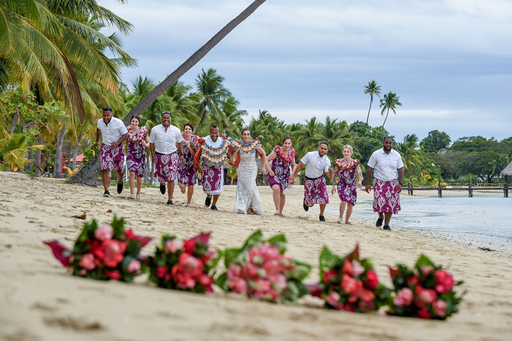The bridal party runs towards the camera with ginger bouquets in the foreground