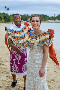 The stunning bride leads her groom as they walk on the beach