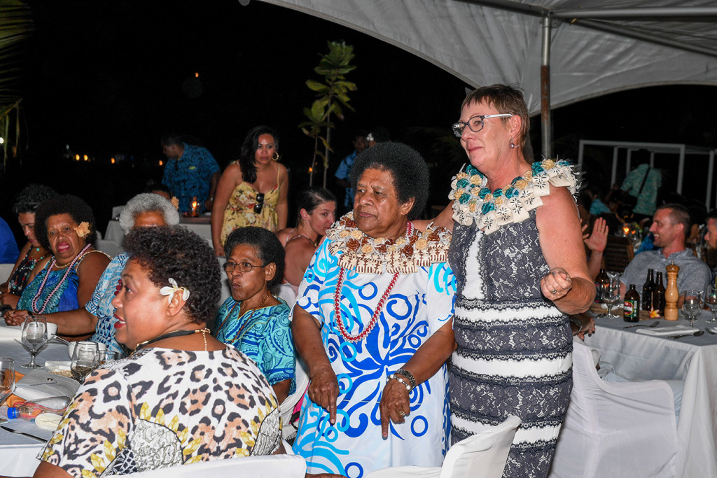 The bride and groom's mothers donned in Fiji flower wreaths stand up and dance during performances