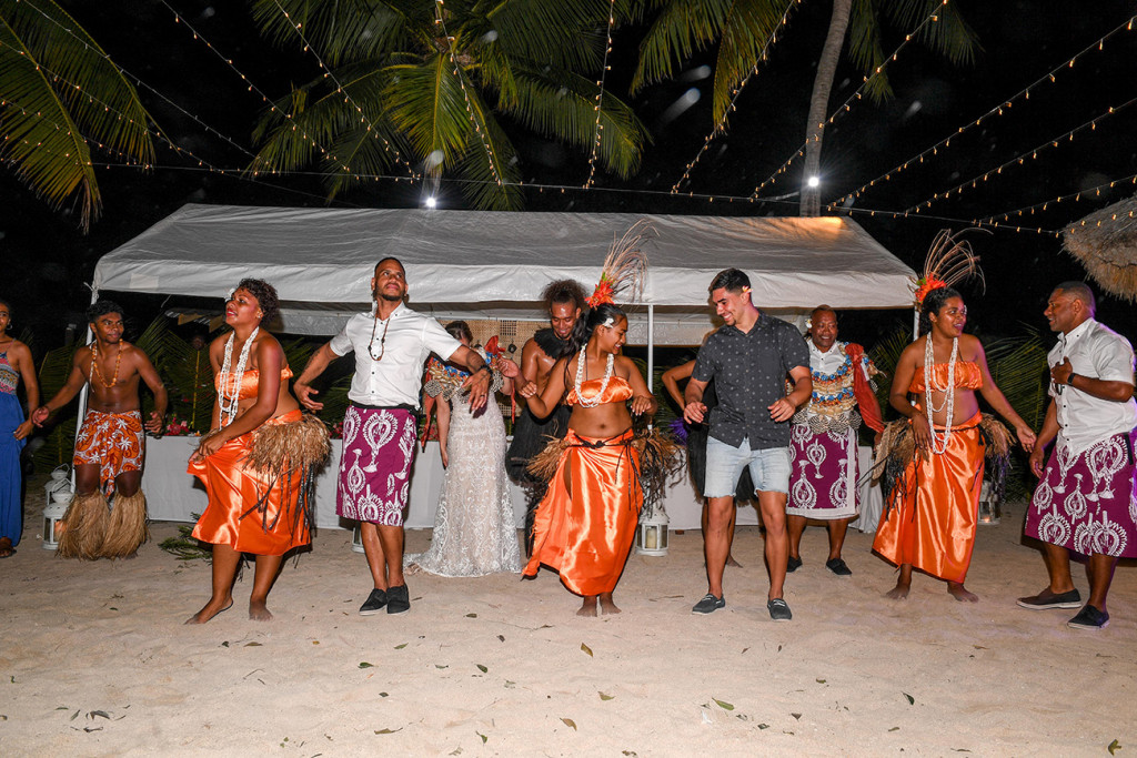 Bridal party join the dancers dressed in orange on the beach dance floor