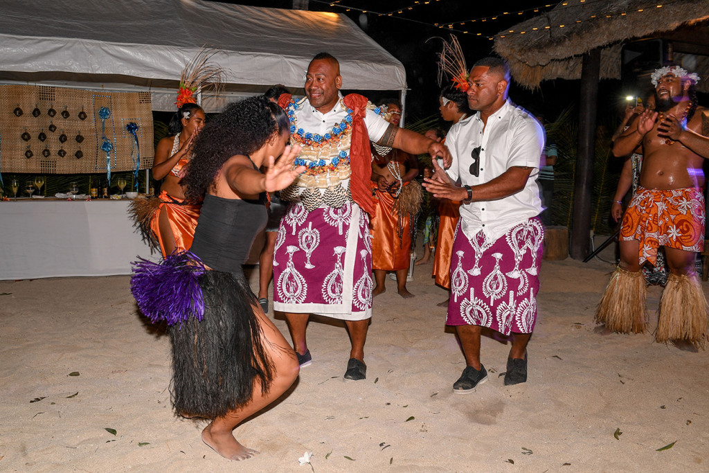 Fiji performer in black and purple sisal skirt dances with groom