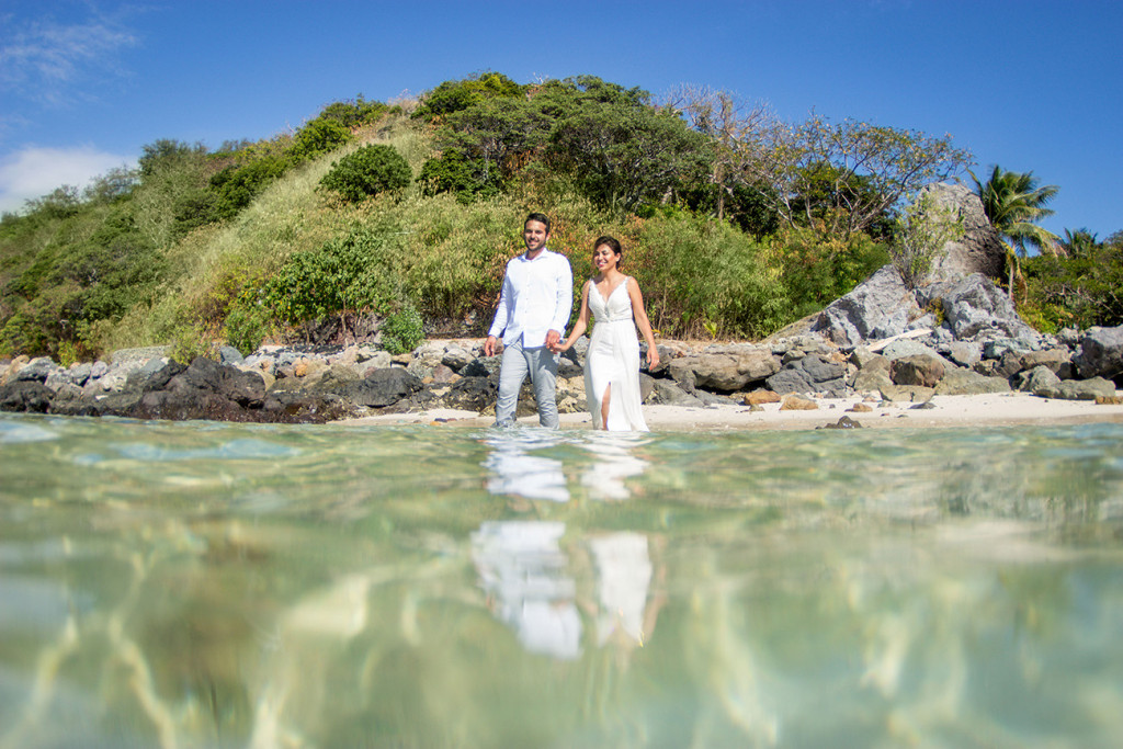 Reflections of the couple as they wade through the clear waters at Castaway Fiji