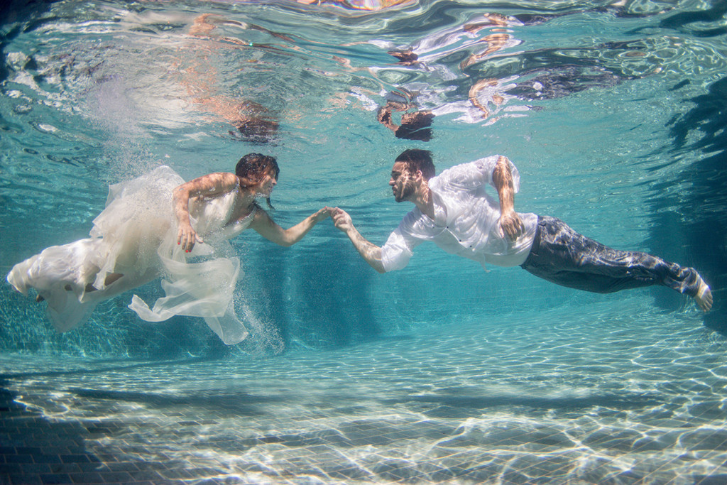 Groom reaches out for his magnificent bride underwater