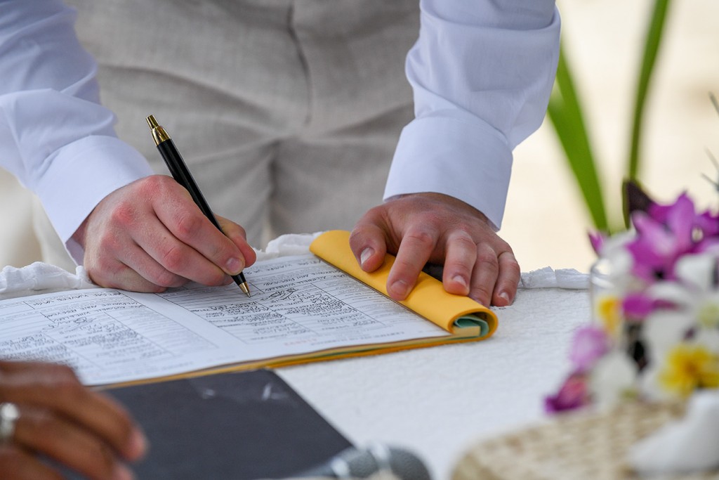 A closeup of the groom signing the marriage certificate