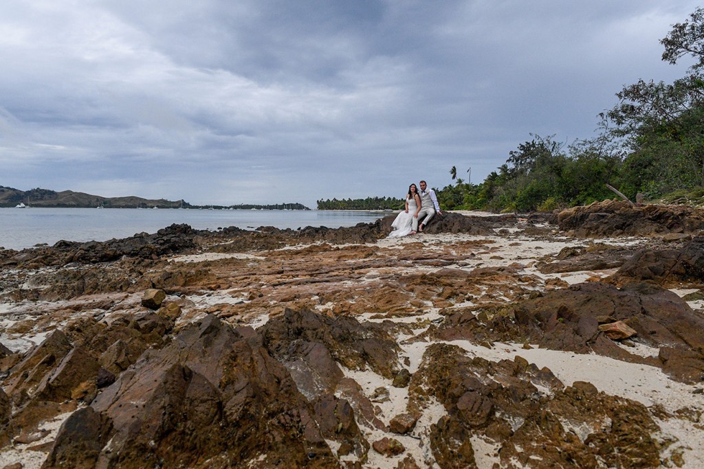 The newly weds pose on beach rocks at Plantation Island Resort Fiji