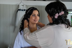 The bride smiles as her necklace is put on her