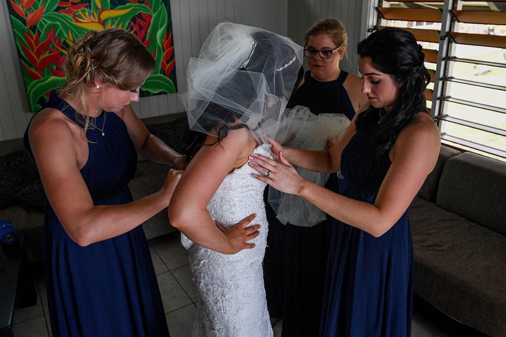 The bridesmaids help the bride fit into her wedding dress