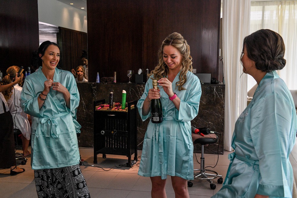 A bridesmaid pops open the champagne bottle