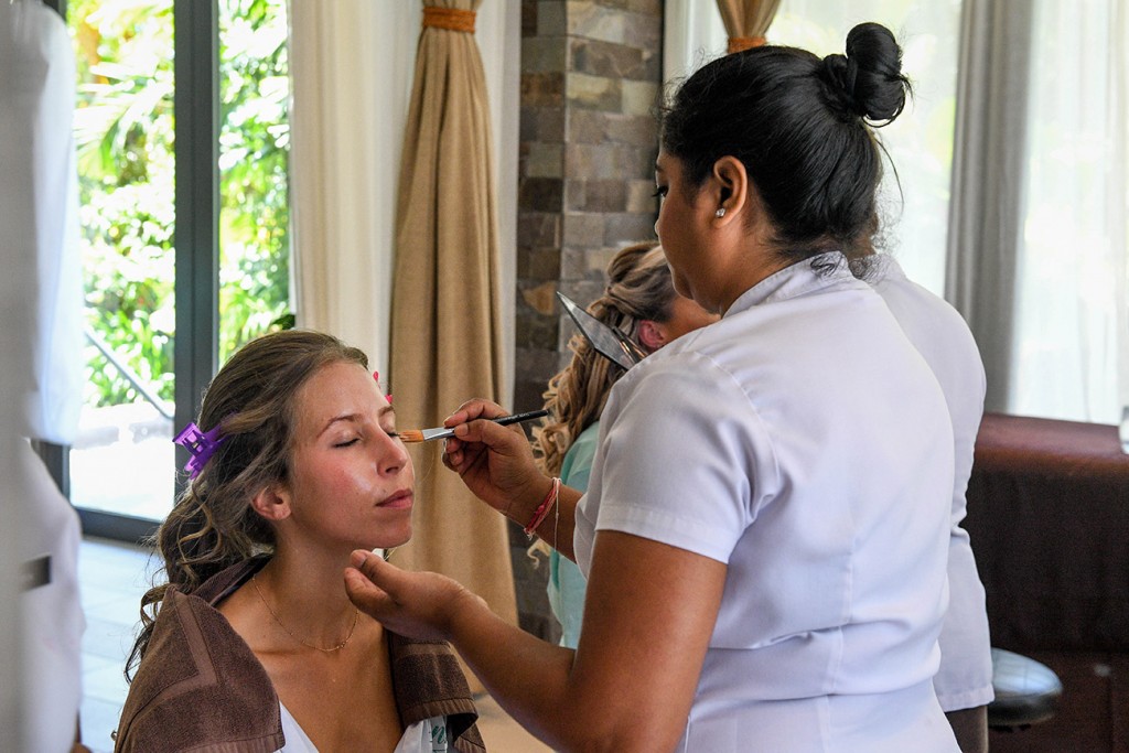 A bridesmaid closes her eyes as her makeup is touched up