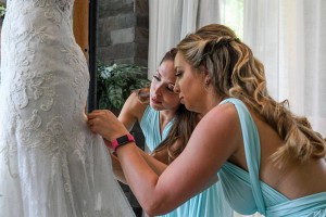 The bridesmaids help the bride slip into her dress