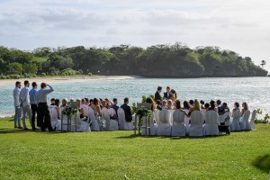Guests watch as the married couple says their vows overlooking the turqoise Pacific