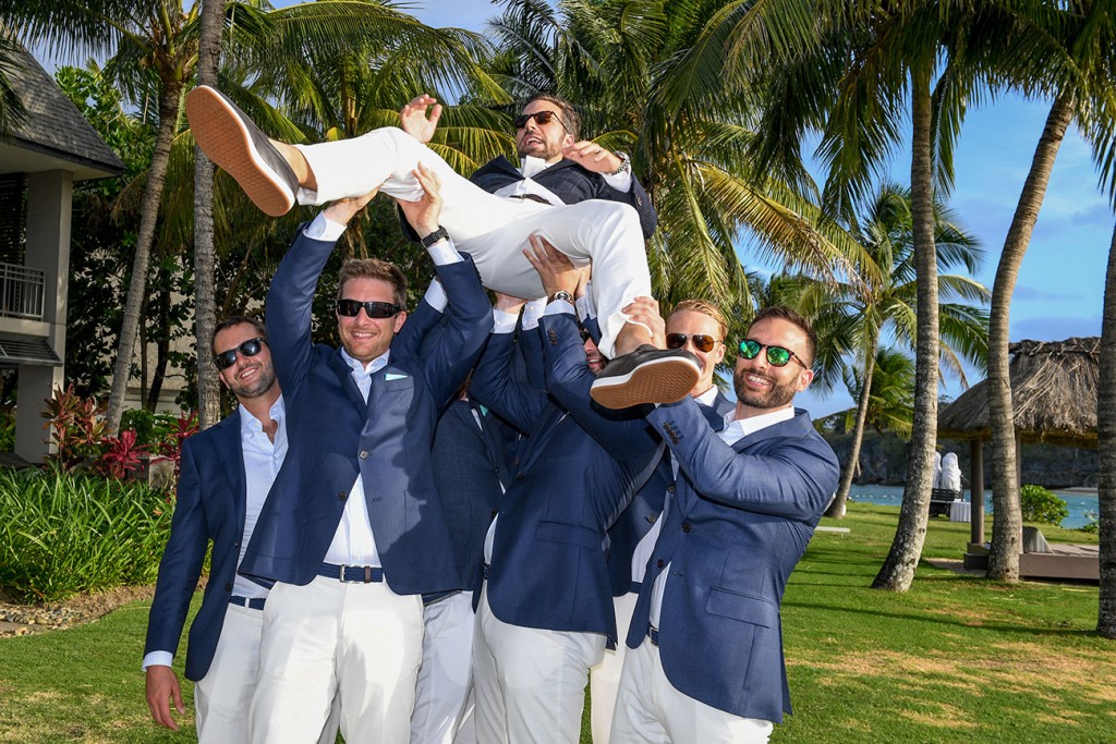 The groomsmen lift the groom above their head