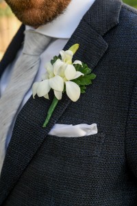 A closeup of the groom's fresh flower frangipani boutonniere