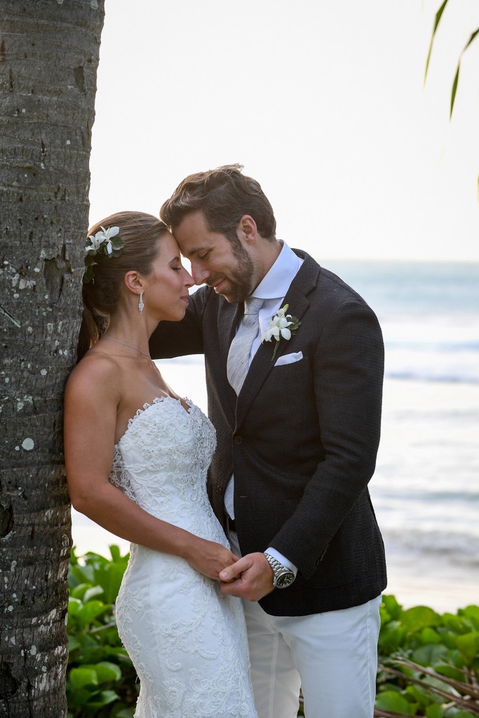 The newly weds share an intimate moment against a palm tree