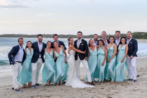 The bridal party poses for a photo on the beach