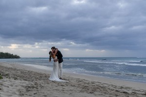 The newly weds kiss on the shore against a Fiji sunset