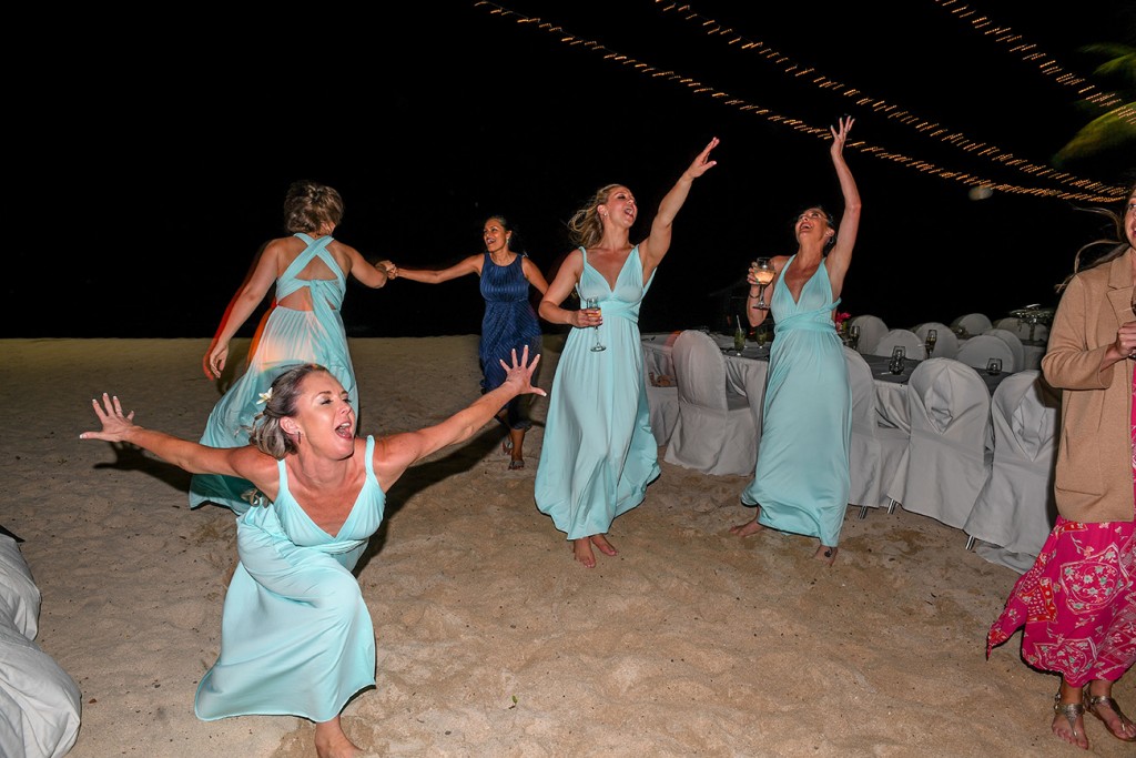 The bridesmaids dance crazily at the beach wedding reception