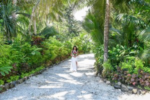 The bride walks down an aisle of palm trees