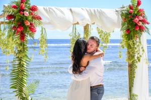 The newly weds hug against the azure ocean