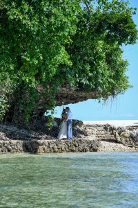 The newly weds kiss under a gigantic coral rock at Savasi Fiji