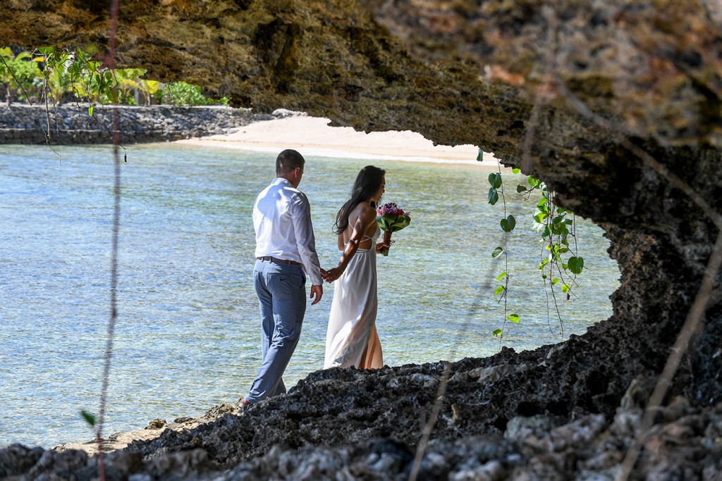 The bride leads her groom behind the coral rocks at Savasi Fiji