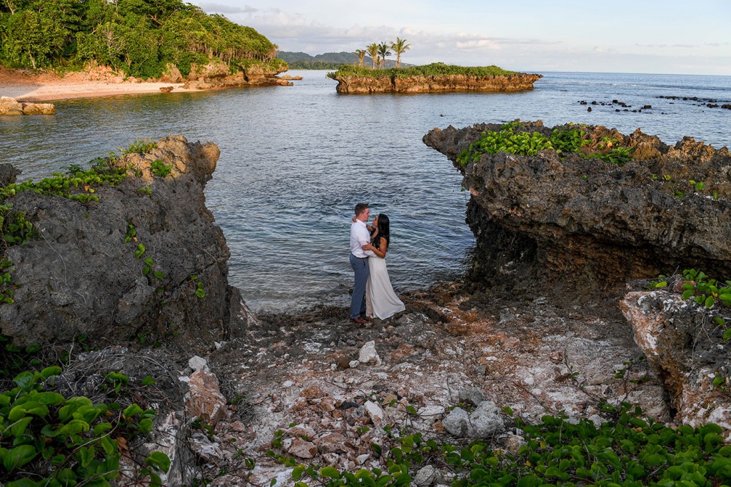 The newly weds cuddle on the coral beach at Savasi