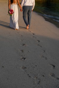 The newly-weds leave footprints as they stroll on the beach
