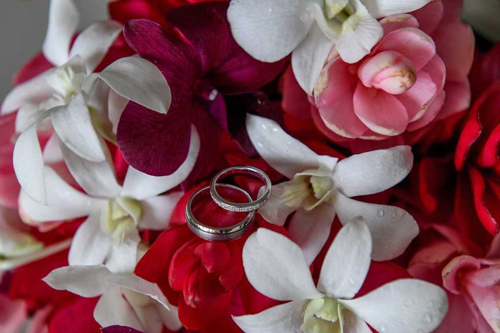 Silver and diamond rings nested on red and white frangipani flowers