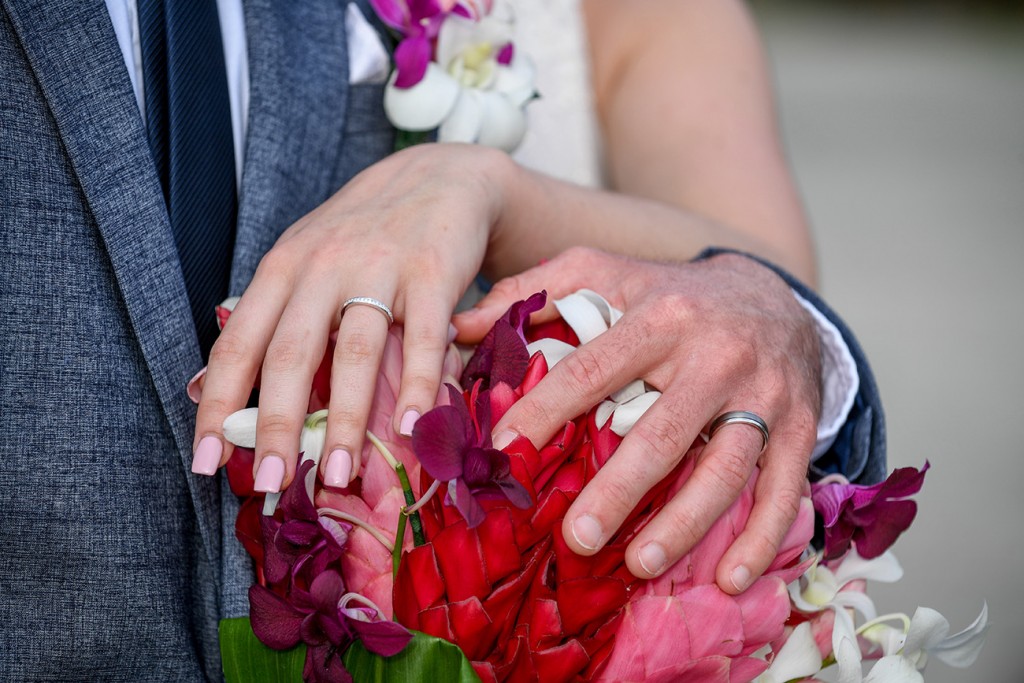 Newly married couple show off their rings on a bouquet of island flowers bouquet
