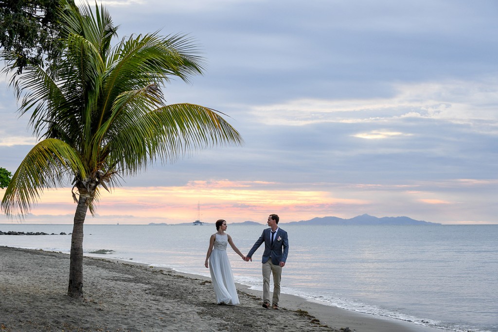 The newly-weds walk hand in hand on the shores of the Pacific Ocean